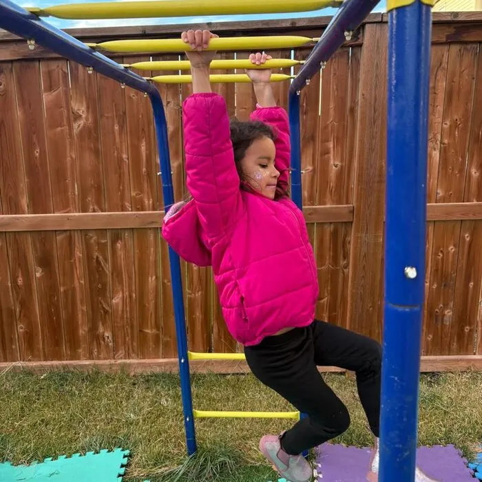 Niña en las barras de mono del patio