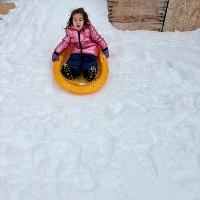 Niña deslizándose en trineo sobre la nieve