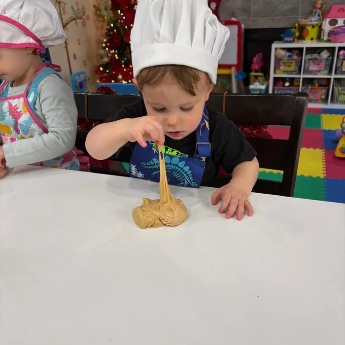 Niño con gorro de chef comiendo masa