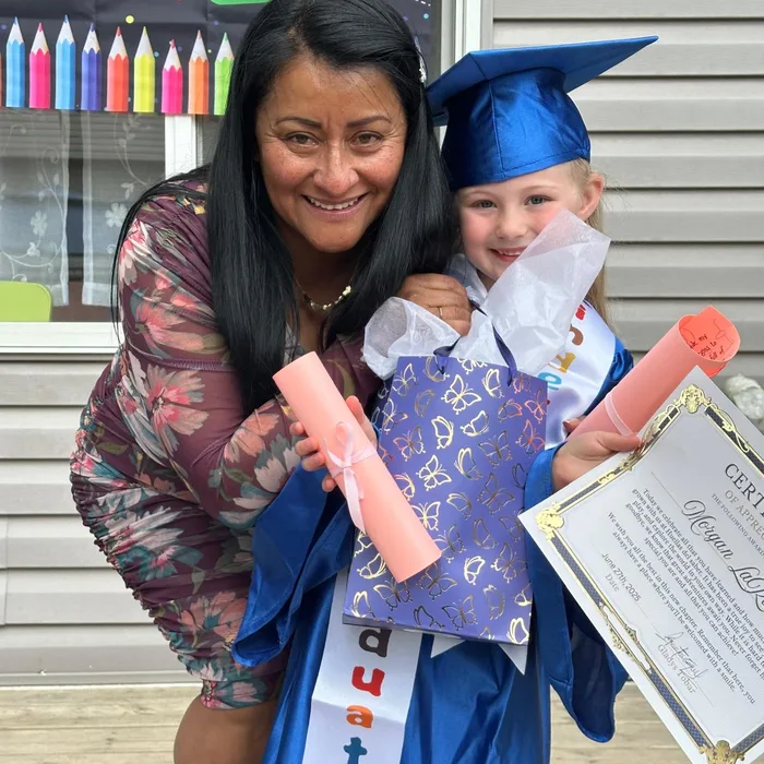 Gladys celebrando con una niña graduada