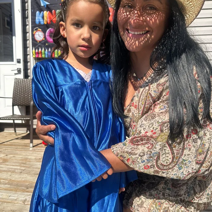 Gladys abrazando a una niña graduada