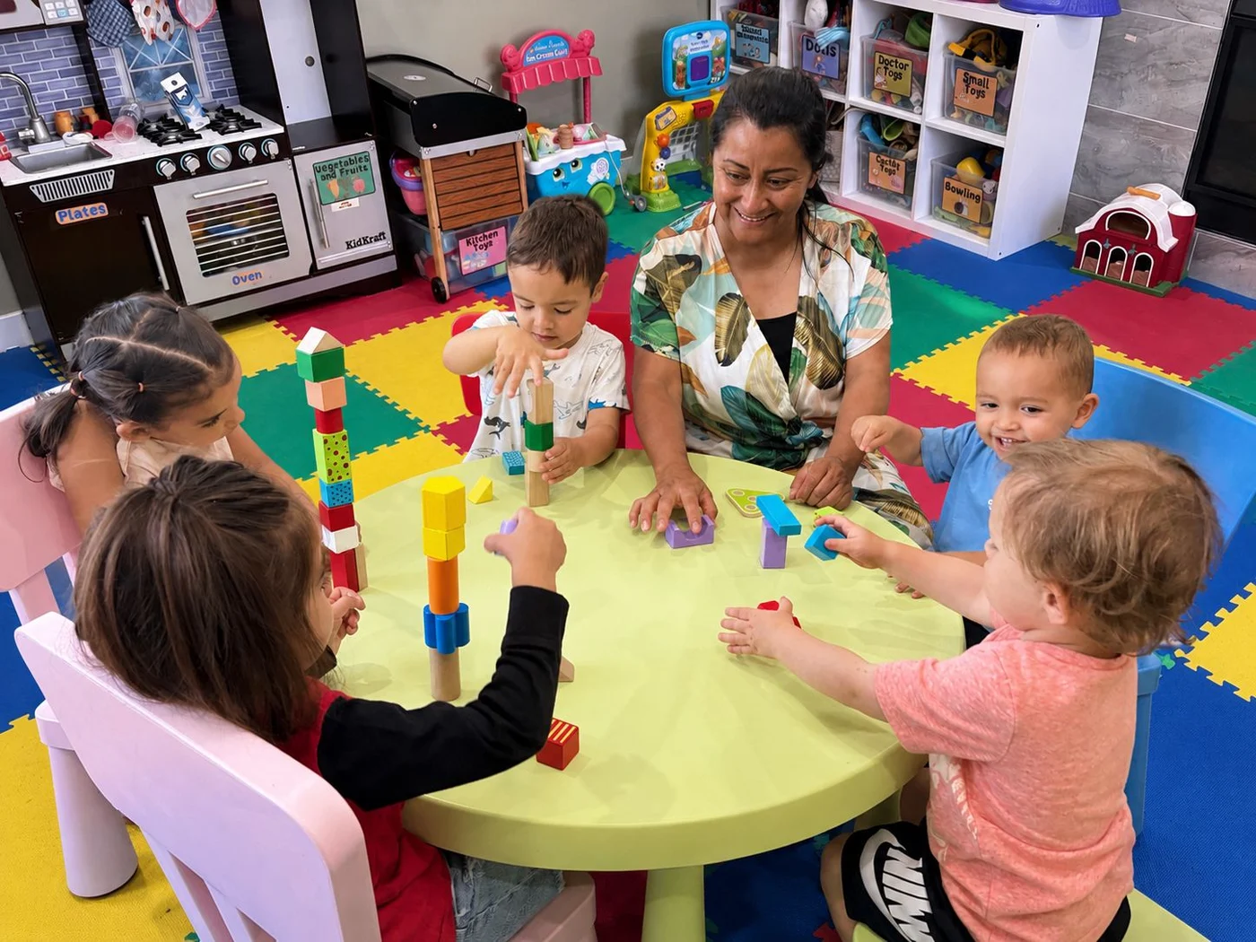 Gladys jugando con bloques junto a un grupo de niños en Dayhome Huellas del Saber